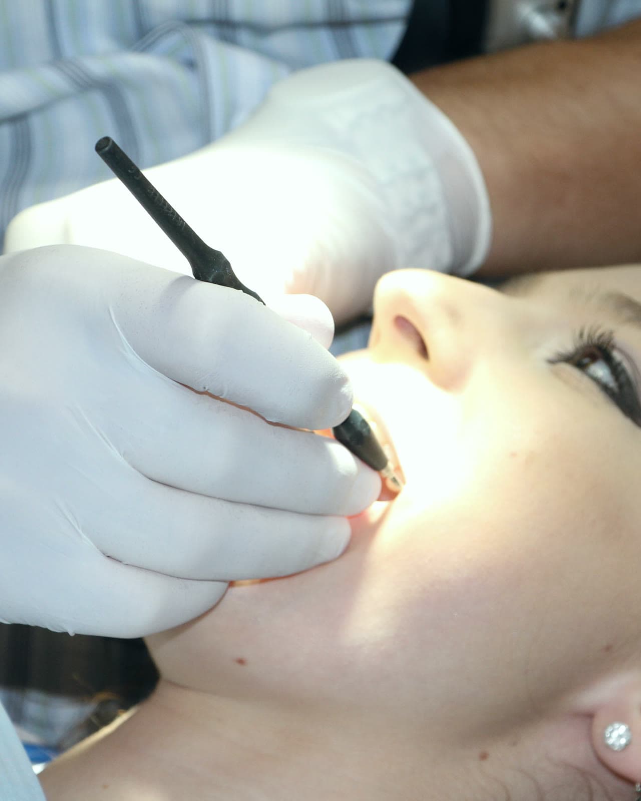 A hygienist examining an adult patient's teeth with a mirror